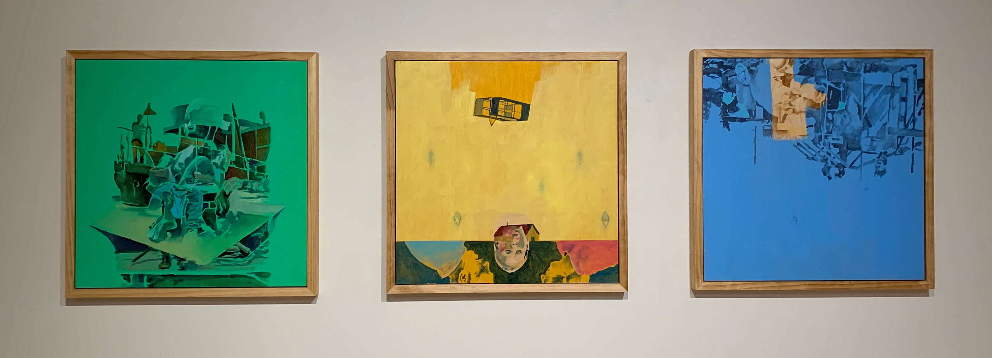 three paintings hung side by side, the first is predominately green with a fractured image of a child on a floating vessel, the second is predominately yellow with a box kite floating high above a house on a plain, superimposed over the house and land are three upside down portraits, the third is predominately blue and features the image of a young person peering through a scope, they are amidst a clutter of metal beams.